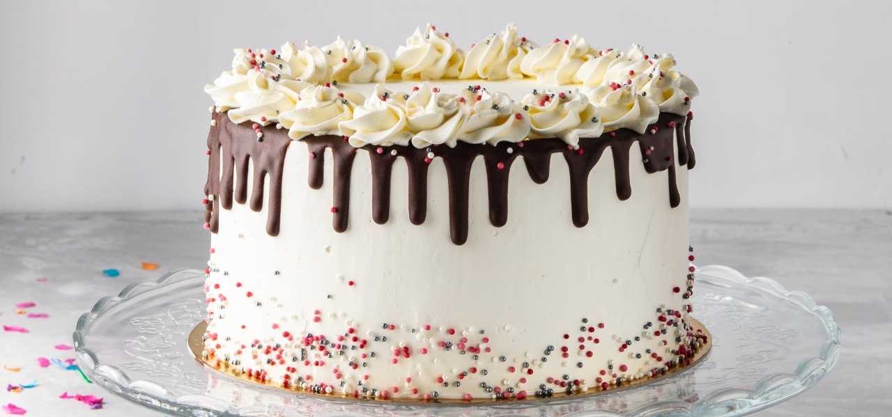 A cake with smooth sides and piped icing on the top