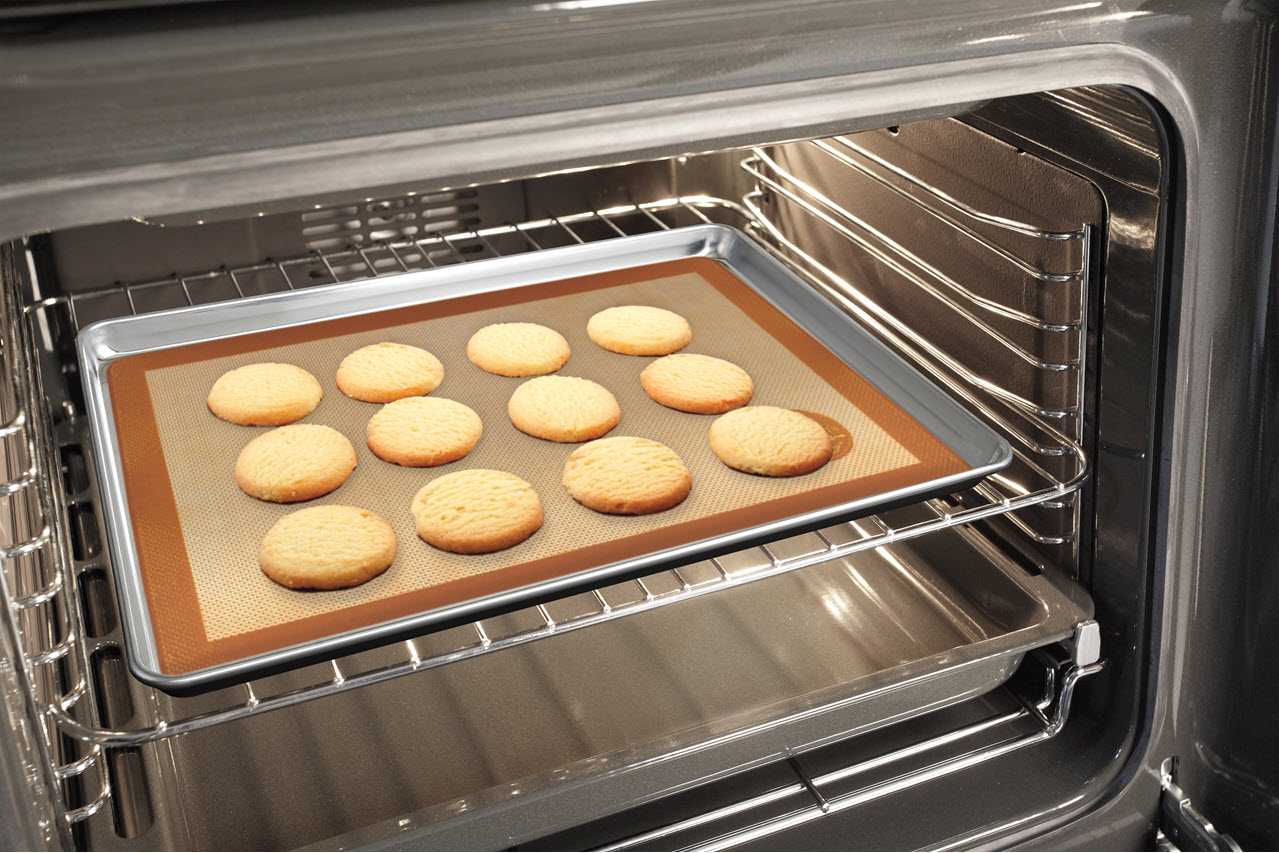 The Mrs Andersons Baking silicone baking mat on a sheet pan in the oven with cookies