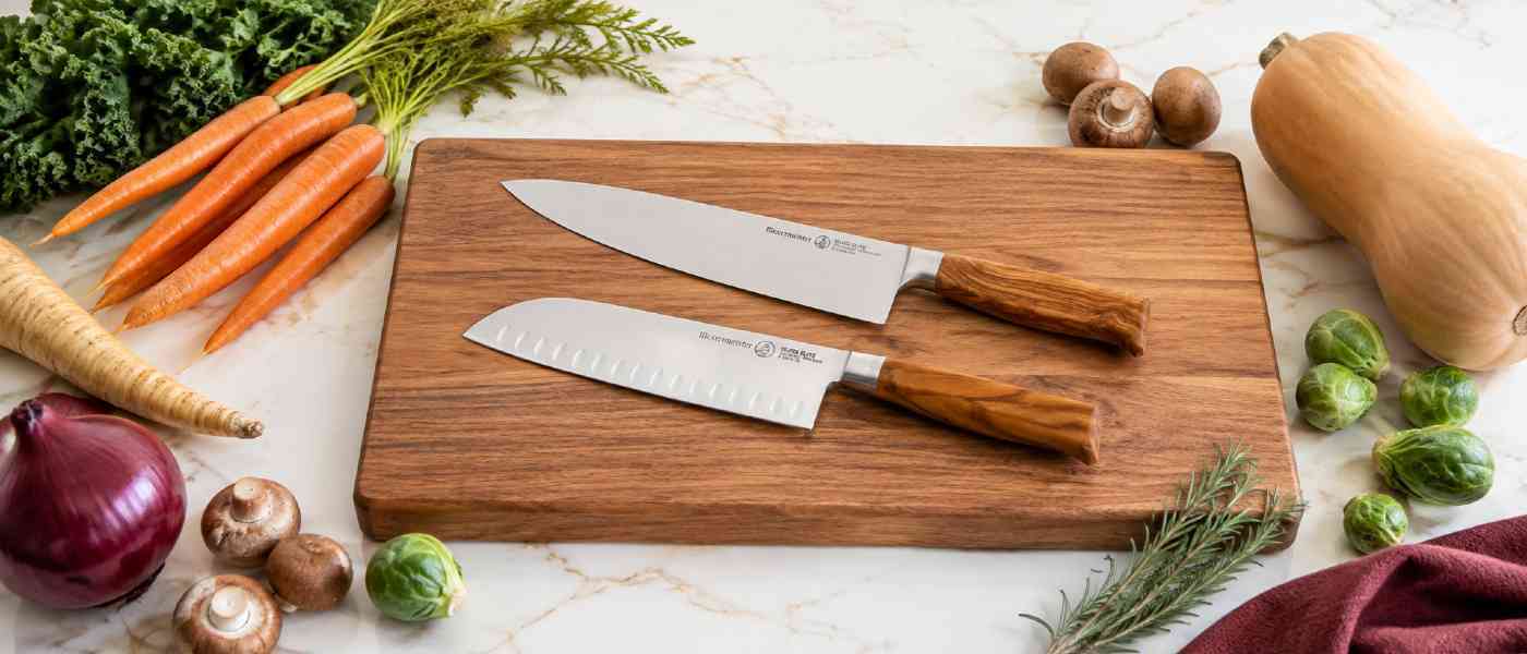 The Messermeister Oliva Elite Chef Knife and Santoku Knife on a cutting board ready for Fall vegetable prep