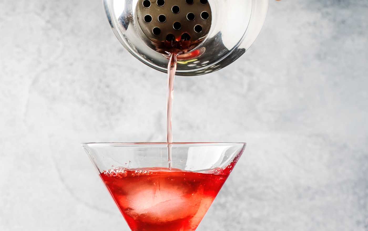 A cobbler shaker pouring a cocktail