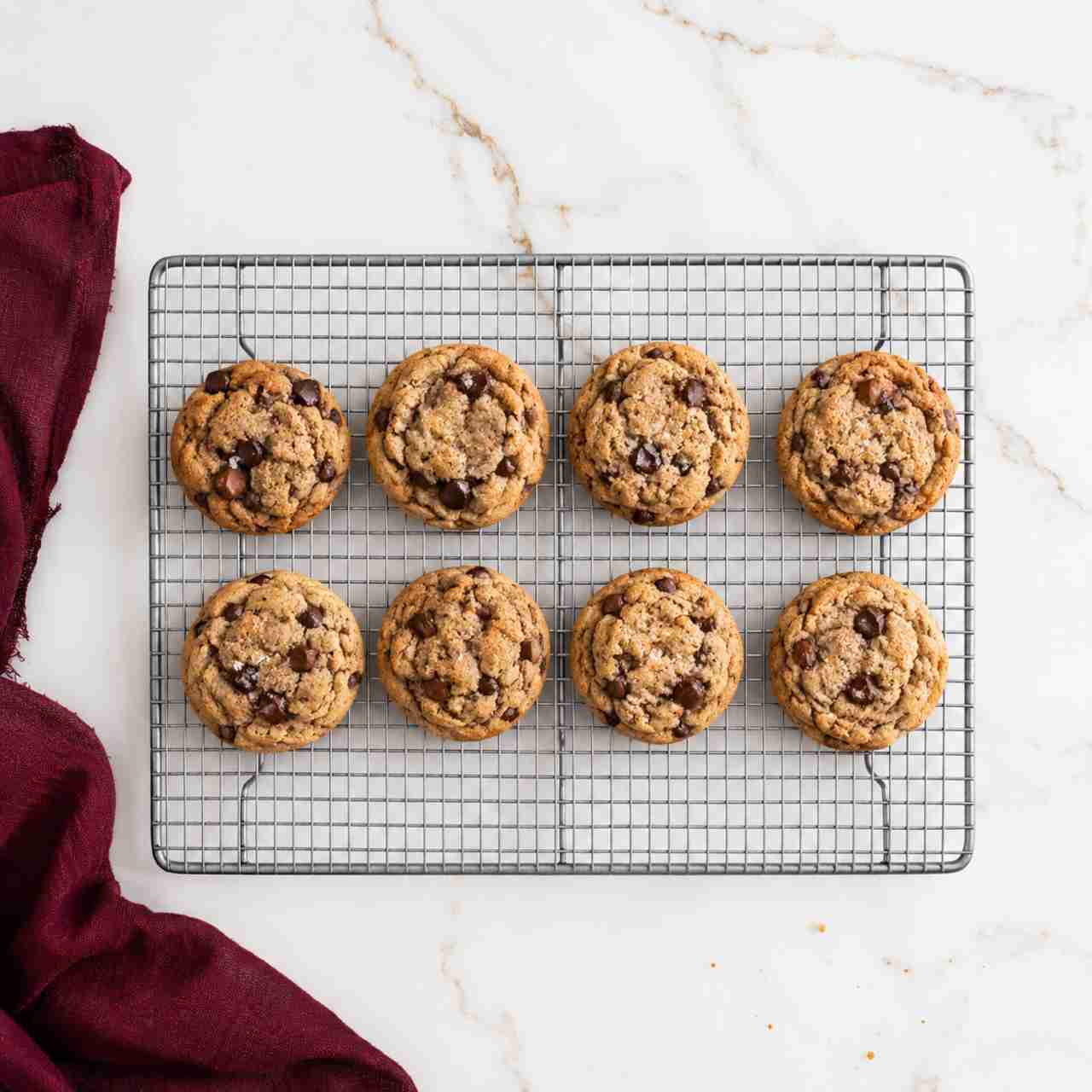 An overhead view of 8 chocolate chip cookies on a cooling rack.