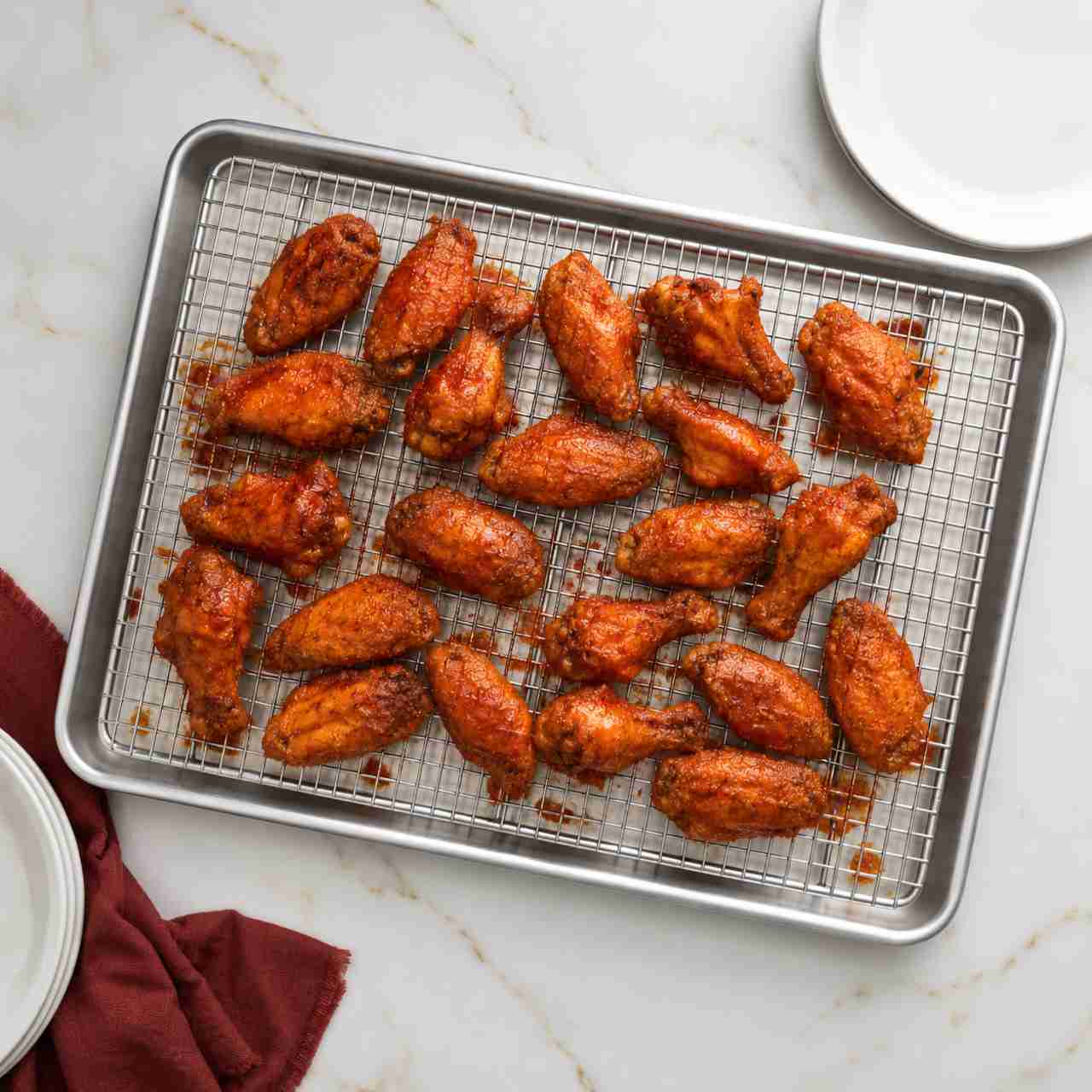 A cooling rack in a sheet pan with roasted Buffalo wings