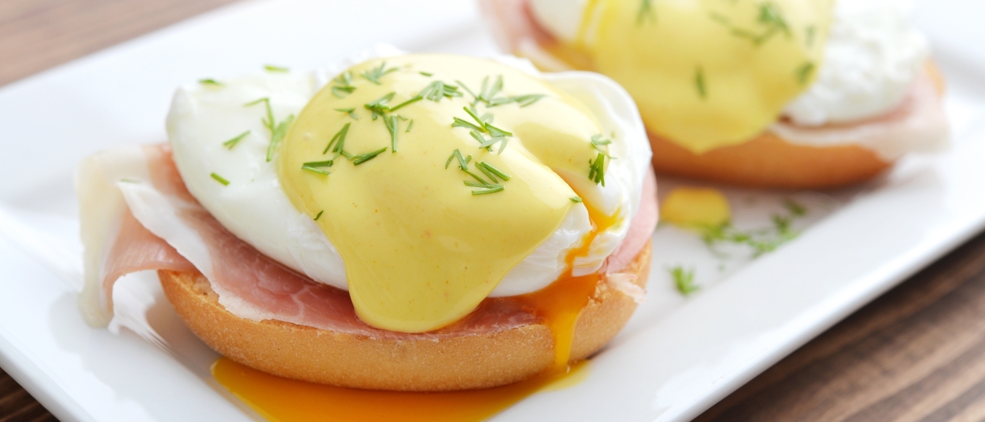 A close up of eggs benedict on a white serving tray