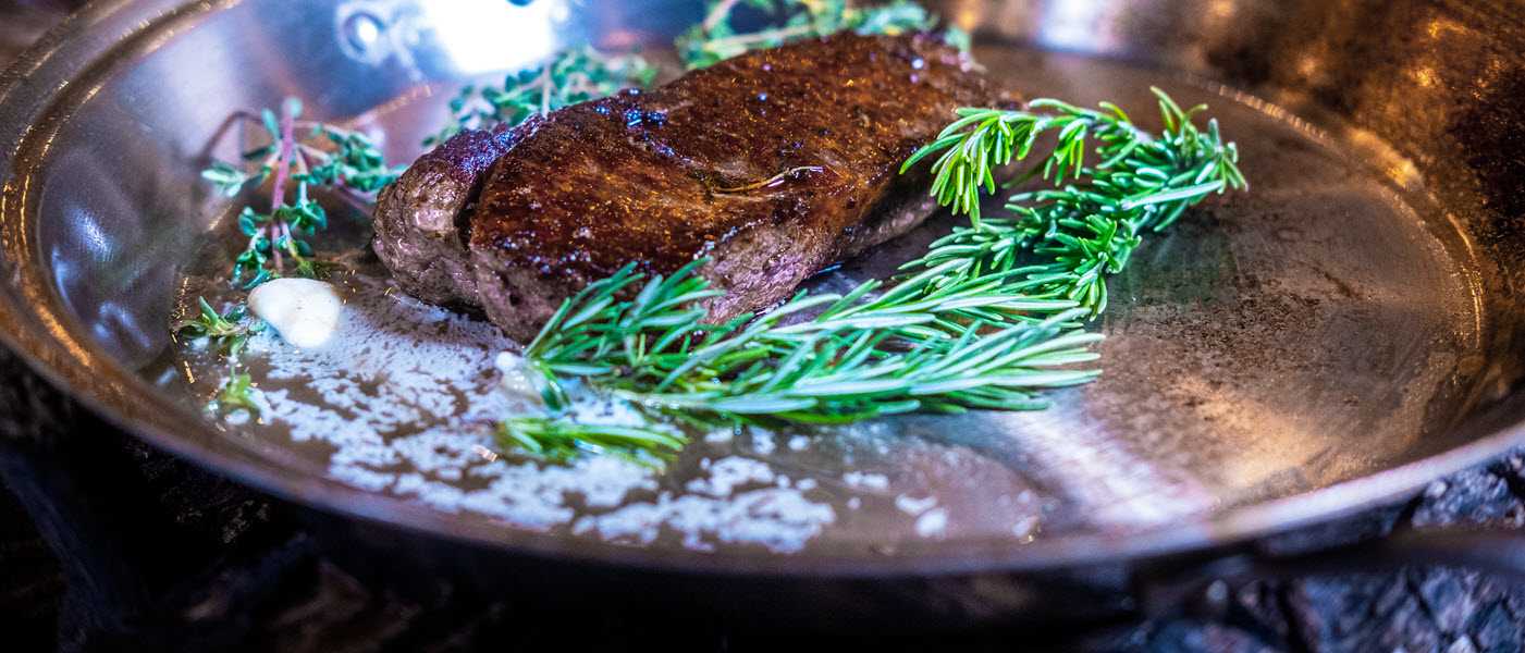 Steaks cooking with butter and rosemary in the Heritage Steel French skillet