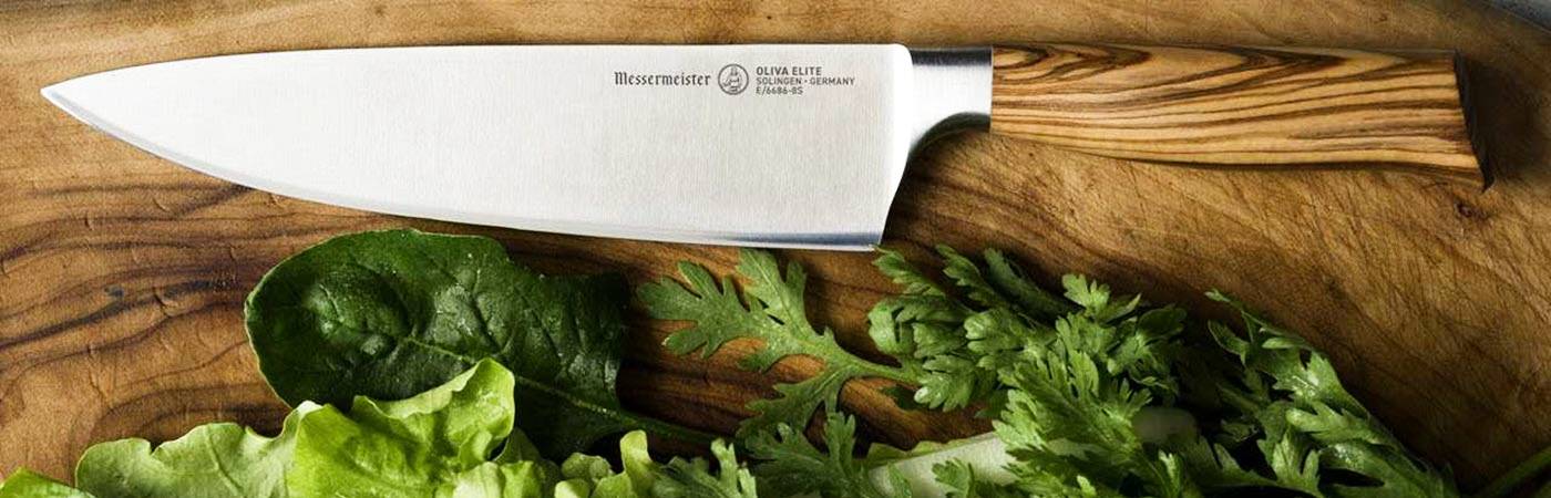 The Messermeister Oliva Elite Stealth Chefs Knife on a cutting board with lettuce