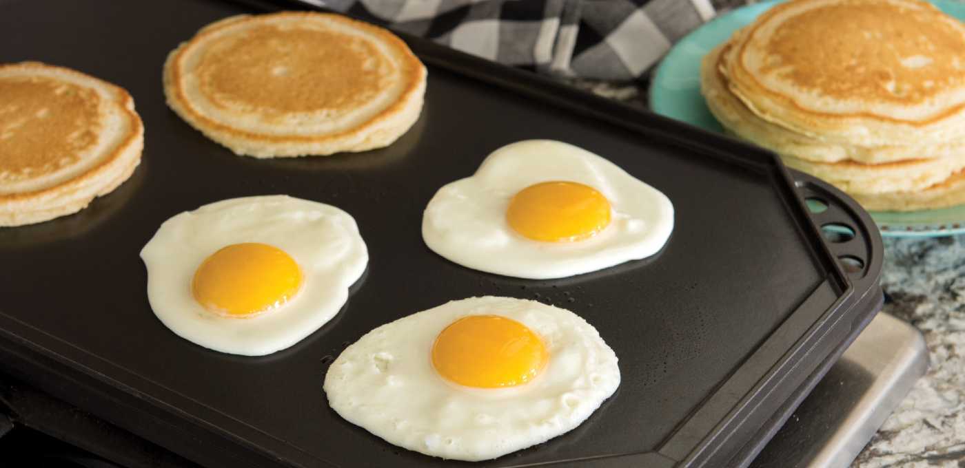 Pancakes and eggs cooking on a Nordic Ware reversible griddle